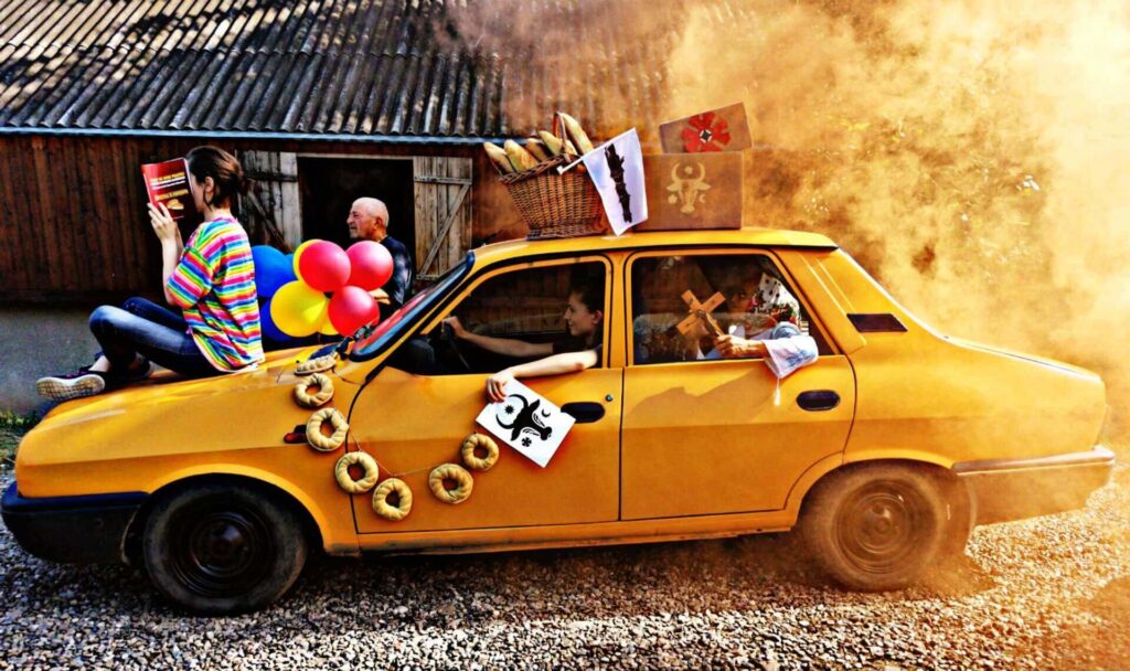 Dacia încărcată cu produse dipimacu – covrigi, pâine și simbolul bourului moldovenesc, tradiție pe roti.